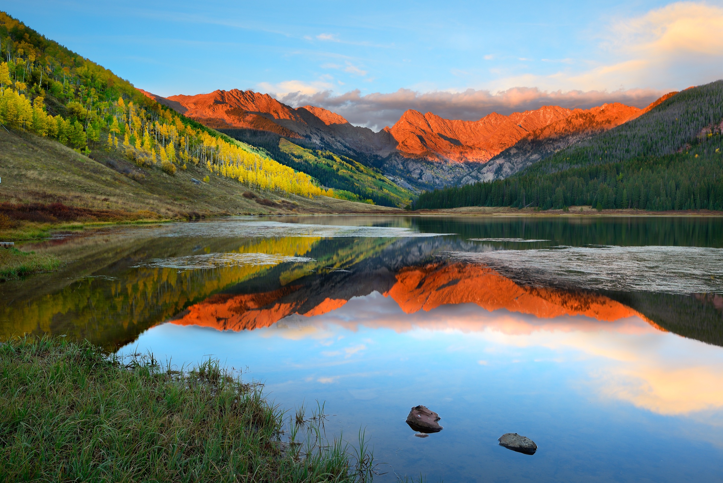 Sunset alpenglow on a mountain range mirrored in a calm alpine lake